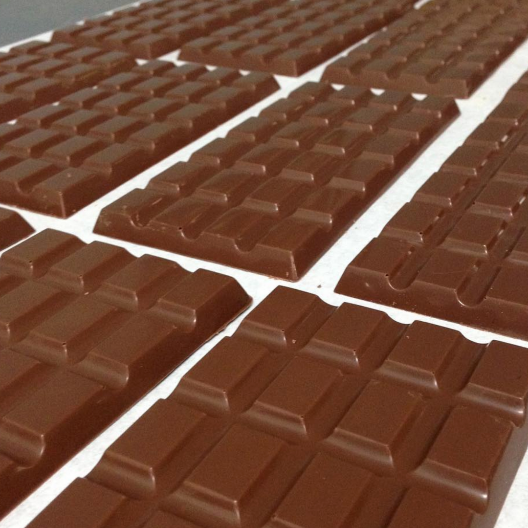 Rows of dark chocolate bars made by Cocoa Manna on a white table top