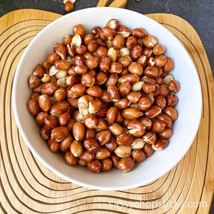 Roasted hazelnuts in a white bowl on a wooden surface, perfect for snacking or baking.